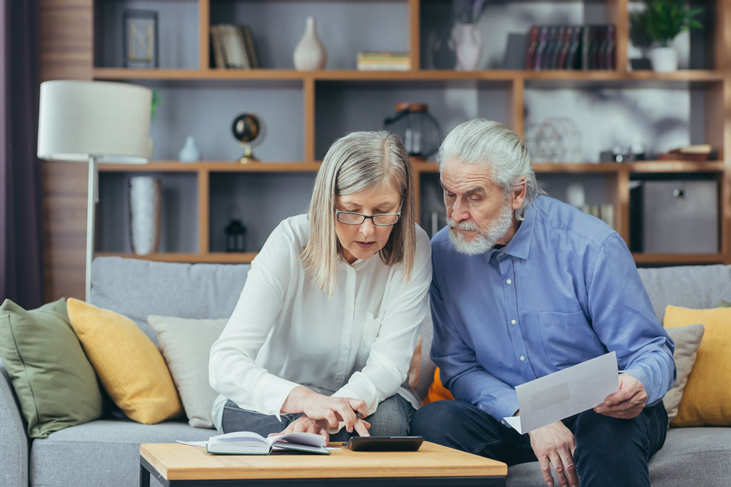 Senior living costs planning with paperwork, calculator, and budgeting notes on a table